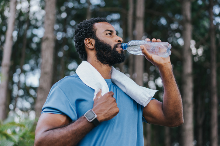 man drinks from a water bottle after a workout